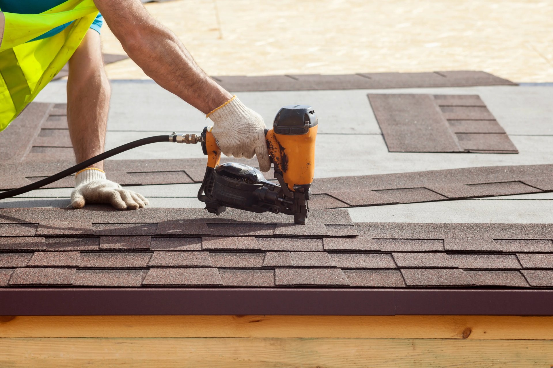 Roofer using a nail gun to install asphalt shingles by roofing contractors in Philadelphia